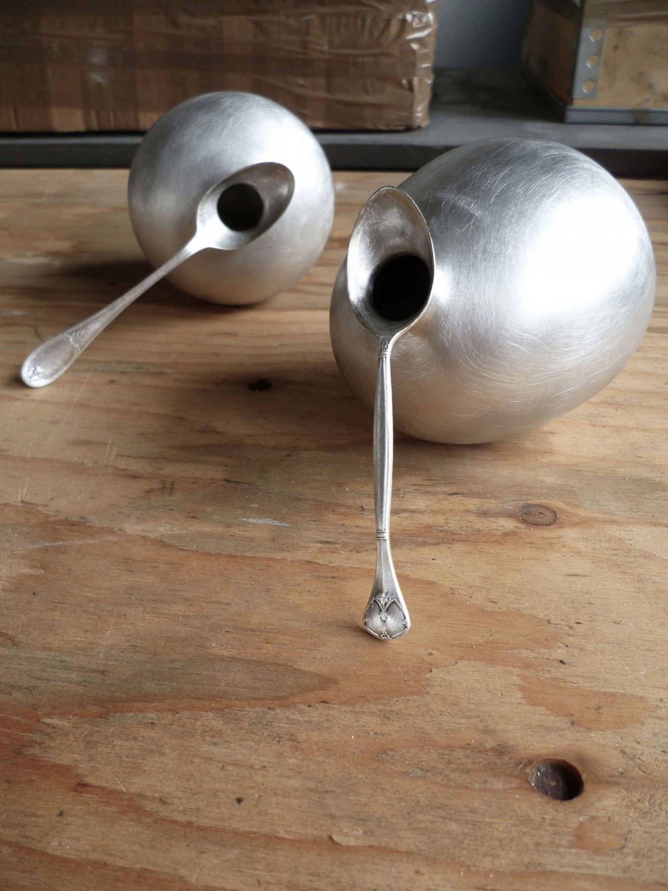 Image of a collection of metal spoons that look like soap bubbles have been blown through the bowls of the spoons