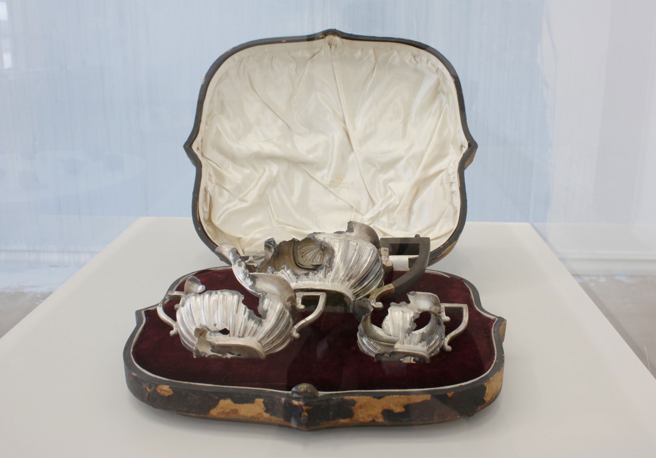 Image of an old silver tea service housed in a wooden presentation bax. The silver has beenattacked with lead that eats silver