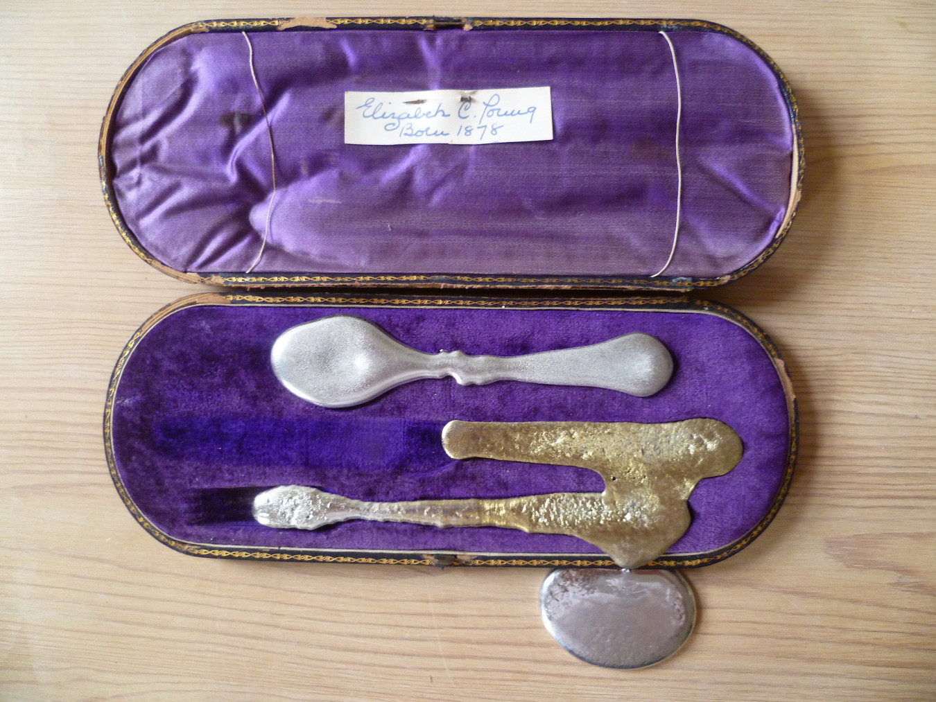 In image of the box lid open, revealing the inside. Pewter cutlery is shown and looks like it's melting slowly.
