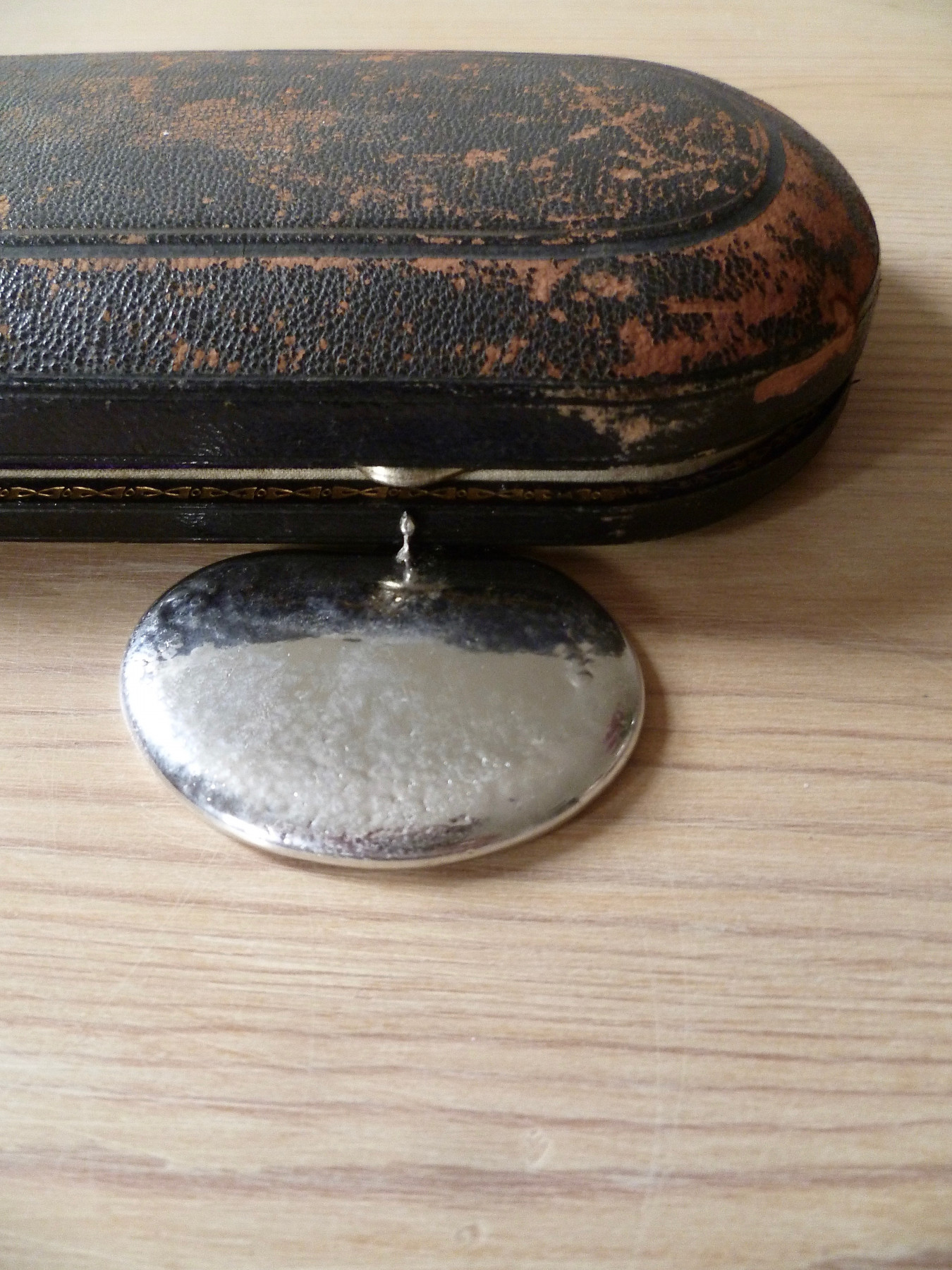 A detailed image of an old presentation box for silver cutlery with a puddle of pewter pouring out.